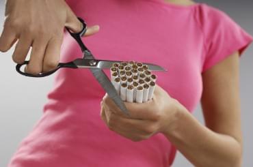 Woman cutting bundle of cigarettes, close-up