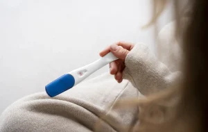 Mulher segura um teste de gravidez com duas linhas vermelhas indicando resultado positivo, ilustrando o tema da fertilidade feminina e até que idade a mulher pode engravidar.