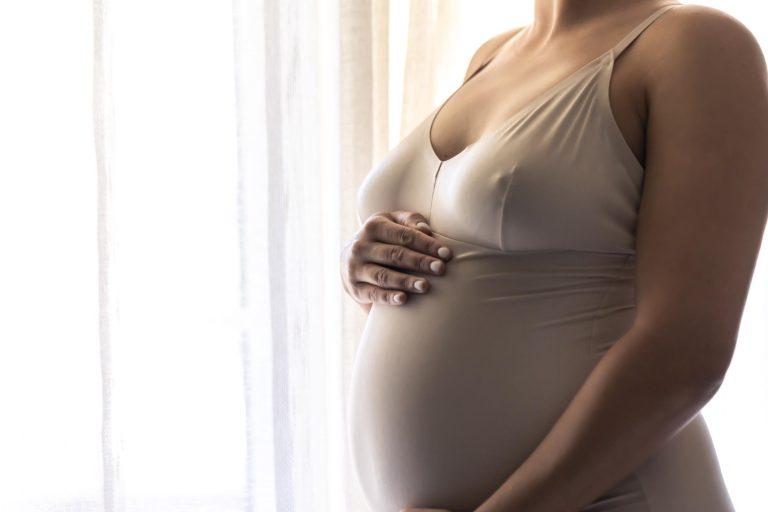 Corpo de uma mulher que conquistou a gravidez depois dos 40 anos segurando a barriga.