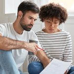 Casal sentado olhando o resultado do espermograma e se perguntando se a azoospermia tem cura