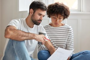 Casal sentado olhando o resultado do espermograma e se perguntando se a azoospermia tem cura