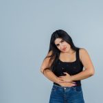 Mulher com a mão na barriga, preocupada com a endometriose umbilical