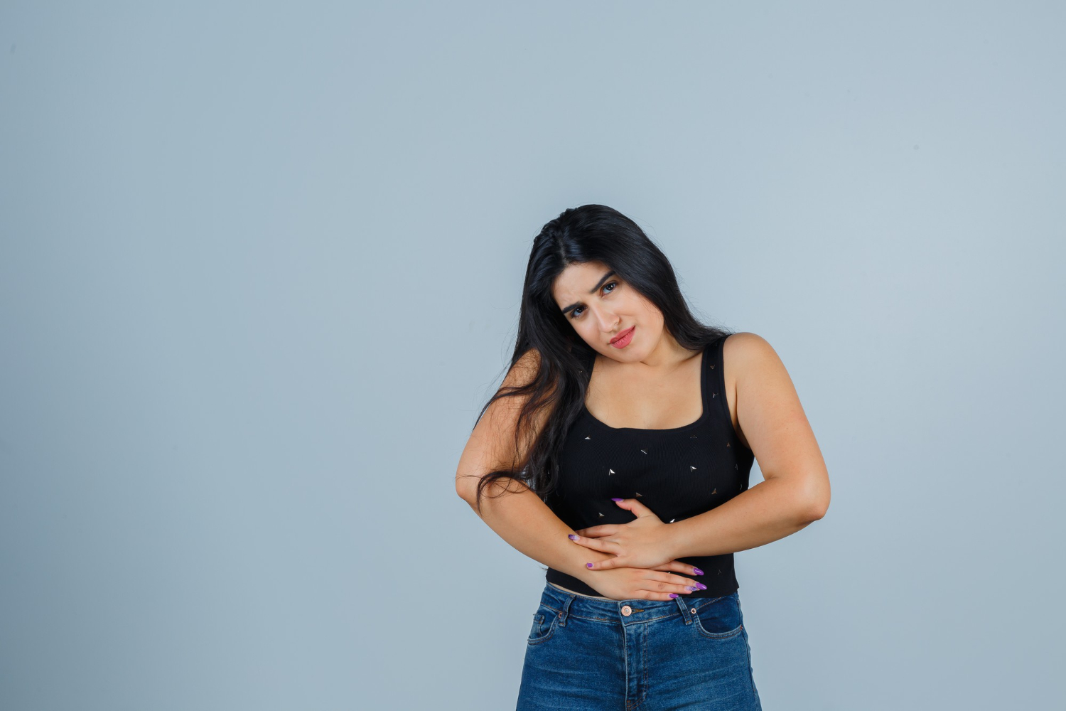 Mulher com a mão na barriga, preocupada com a endometriose umbilical