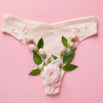 Foto de uma calcinha com algumas flores no fundo, representando o muco cervical.