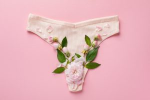 Foto de uma calcinha com algumas flores no fundo, representando o muco cervical.
