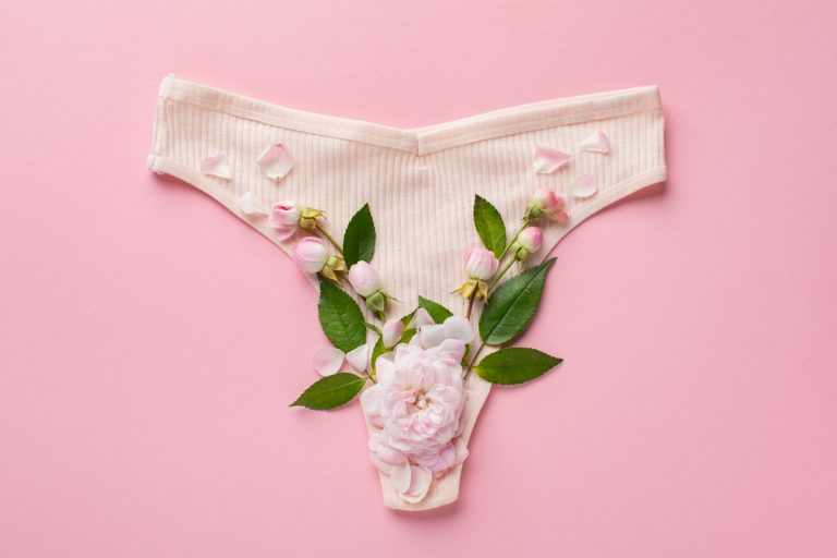 Foto de uma calcinha com algumas flores no fundo, representando o muco cervical.