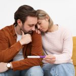 Casal olhando triste para um teste de gravidez e se perguntando o que é infertilidade.