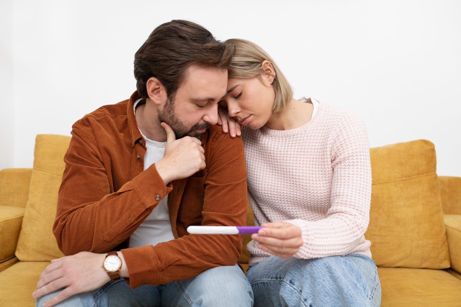 Casal olhando triste para um teste de gravidez e se perguntando o que é infertilidade.