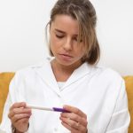 Mulher olhando o teste de ovulação, com dúvidas se ele realmente funciona.