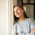 Mulher na menopausa encostada na parede pensando se ainda há possibilidades de engravidar.