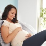 Mulher em gravidez tardia deitada repousando e segurando a barriga.