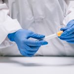 Profissional de laboratório manipulando tubo com amostra para análise de sêmen saudável e fertilidade masculina.