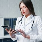 Médica com o tablet na mão para representar o uso de inteligência artificial na seleção de embriões.
