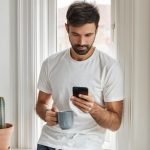 Homem encostado na parede pesquisando o que prejudica a fertilidade masculina.