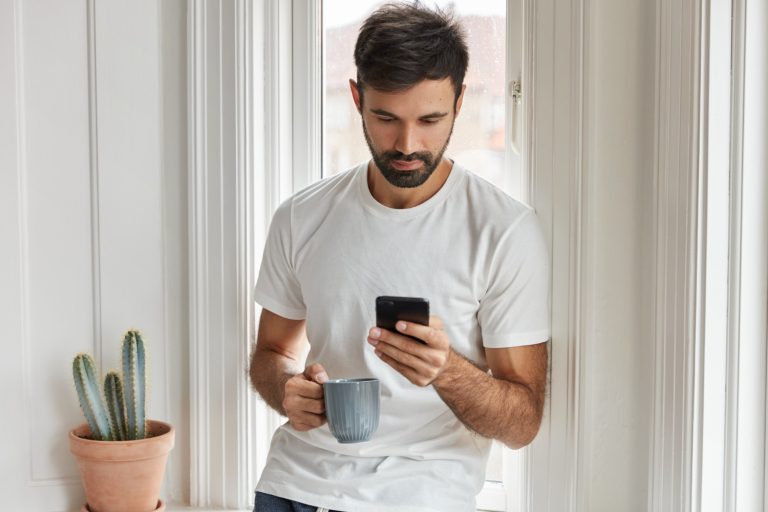 Homem encostado na parede pesquisando o que prejudica a fertilidade masculina.