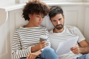 Casal lendo o texto de um papel para entender se é melhor escolher Fertilização In Vitro ou inseminação artificial.