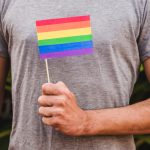 Homem segurando a bandeira LGBT para representar a preservação da fertilidade em pessoas transgênero