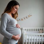 Mulher que optou por produção independente grávida segurando e olhando para a barriga.