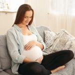 Mulher grávida segurando a barriga feliz com a gravidez por FIV.