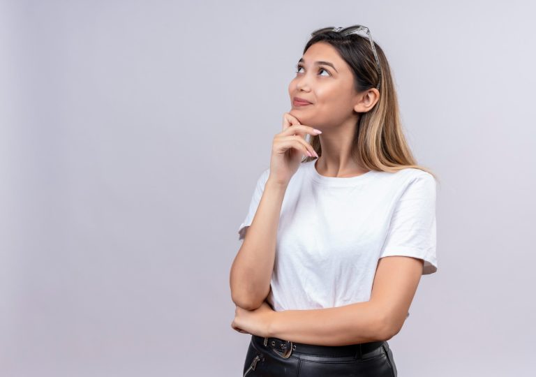 Mulher jovem com a mão no queixo de perguntando se congelamento de óvulos tem efeitos colaterais