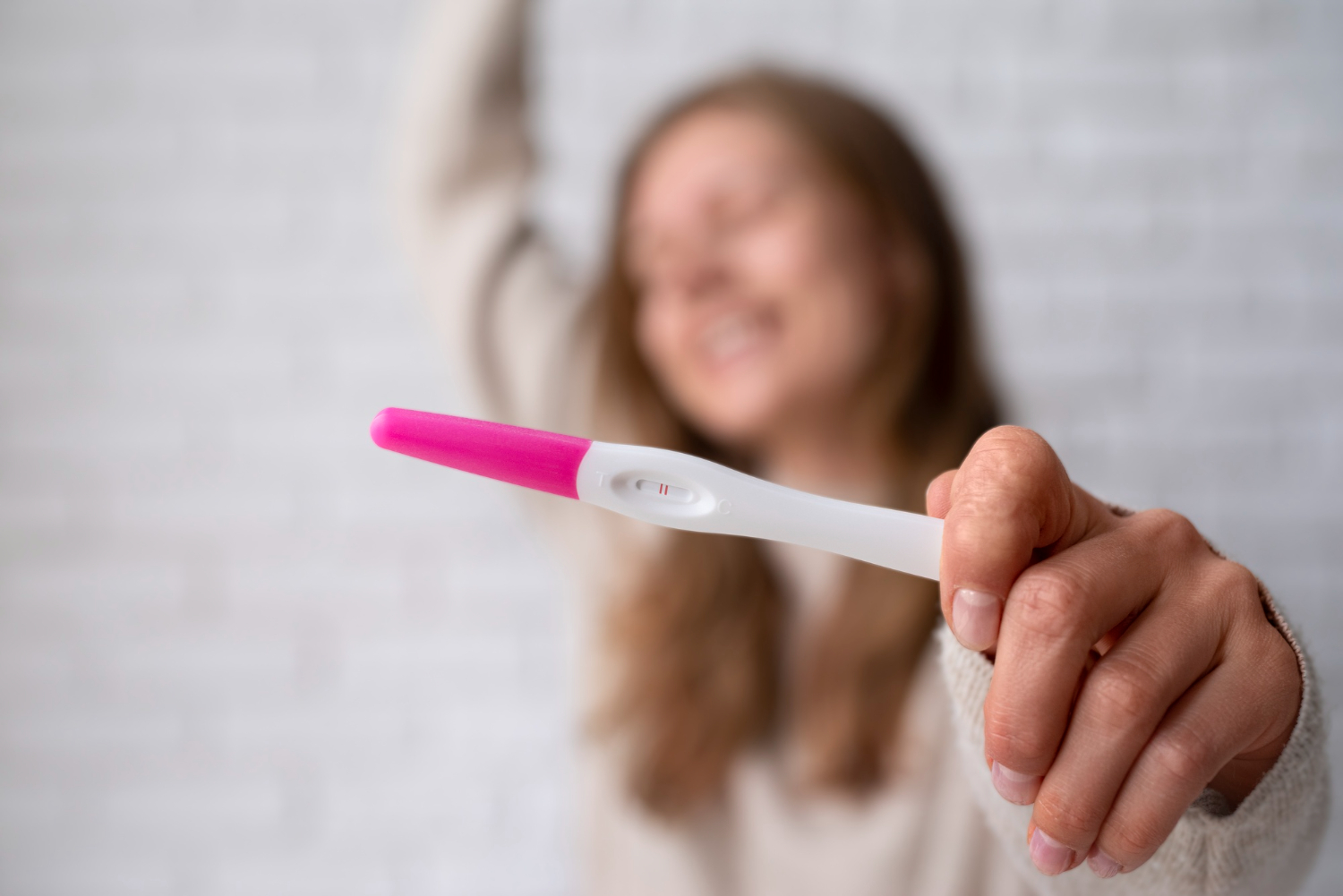 Mulher feliz segurando o teste de gravidez positivo apó9s seguir os passos para conseguir engravidar