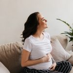 Mulher grávida segurando a barriga após descobrir que é possível engravidar sem as trompas.