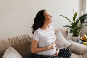 Mulher grávida segurando a barriga após descobrir que é possível engravidar sem as trompas.