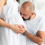 Homem beijando a barriga da mulher grávida depois de recuperar a fertilidade pós-quimioterapia