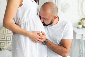 Homem beijando a barriga da mulher grávida depois de recuperar a fertilidade pós-quimioterapia