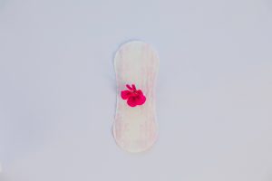 Imagem ilustrativa de um absorvente com uma flor para abordar quando o sangramento após a FIV é normal.
