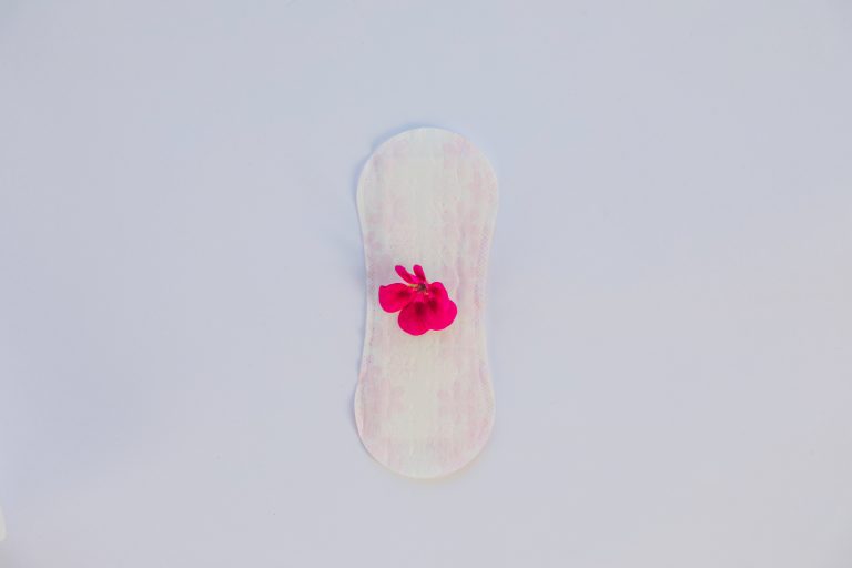 Imagem ilustrativa de um absorvente com uma flor para abordar quando o sangramento após a FIV é normal.