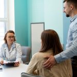Casal em uma consulta com médico de reprodução assistida para entender o tratamento mais indicado: coito programado ou inseminação artificial