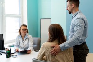 Casal em uma consulta com médico de reprodução assistida para entender o tratamento mais indicado: coito programado ou inseminação artificial