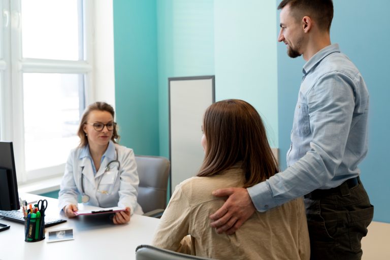 Casal em uma consulta com médico de reprodução assistida para entender o tratamento mais indicado: coito programado ou inseminação artificial