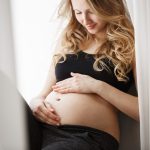 Mulher grávida olhando para a barriga após nova tentativa de FIV