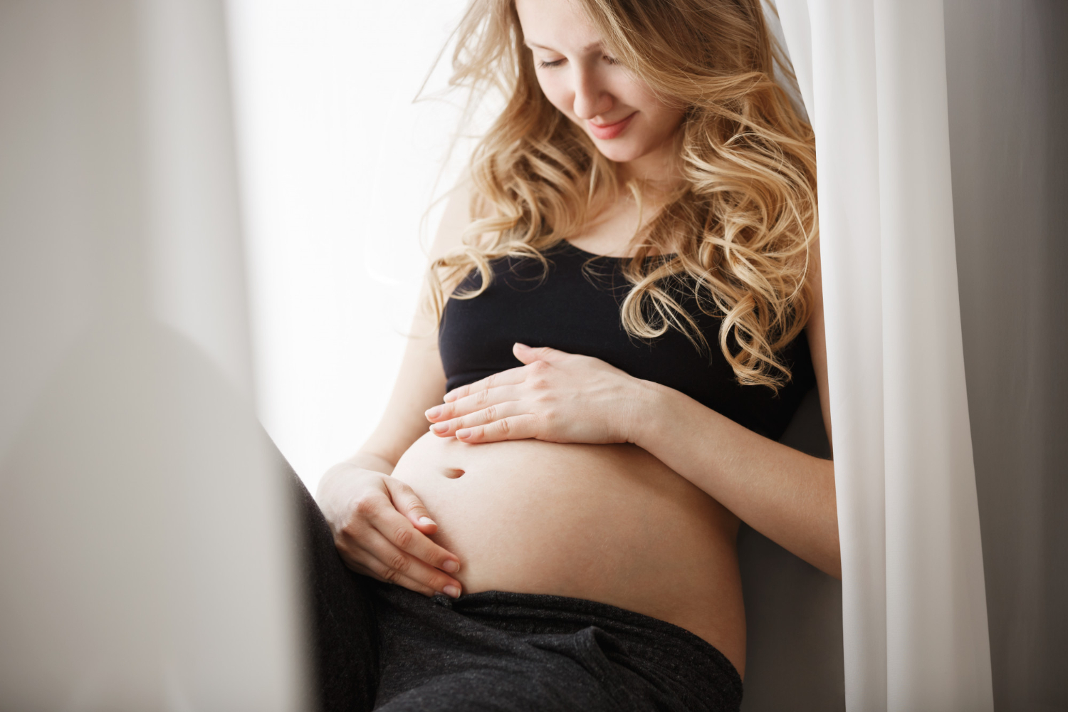 Mulher grávida olhando para a barriga após nova tentativa de FIV