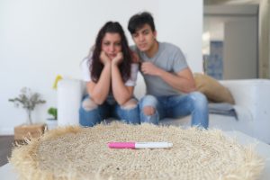 Casal que não consegue engravidar olhando triste para o teste de gravidez.