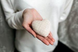 Mãos de uma mulher, receptora de óvulos doados, segurando um coração para simbolizar a atitude.